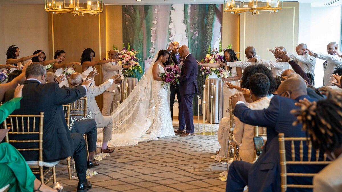 Guests stretch out hands to pray for couple during ceremony at Intercontinental in Washington, DC