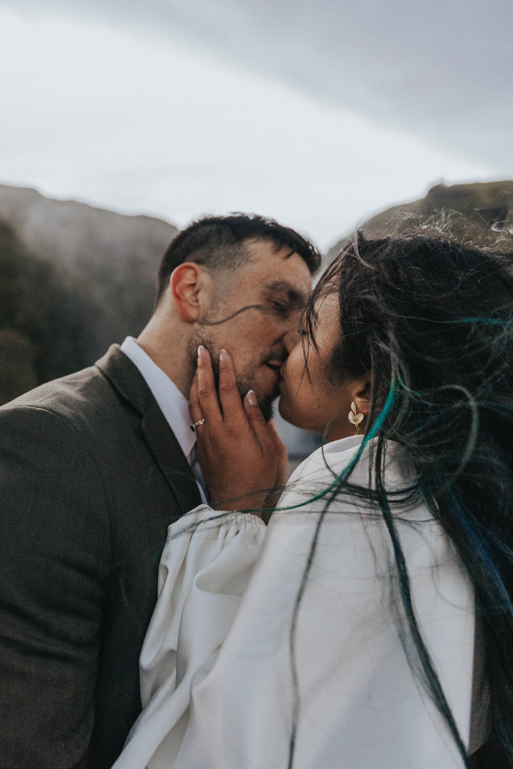 A husband and wife share a tender kiss near a secluded waterfall