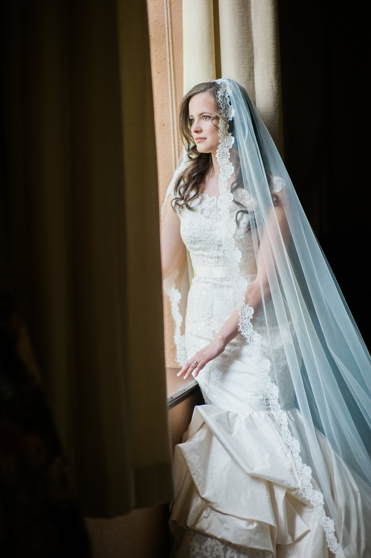 luxury bride in silk cathedral wedding veil by window portrait