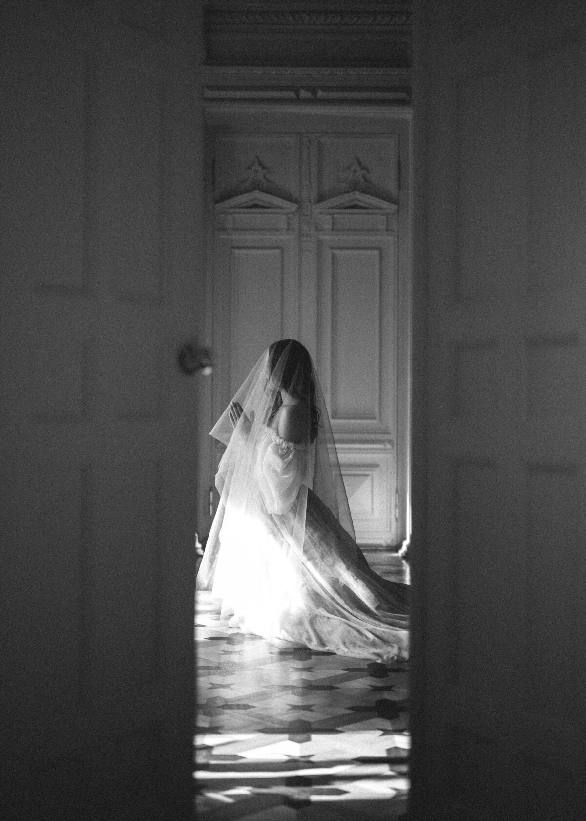 Bride kneeling at the altar wearing lace veil with hands in prayer position