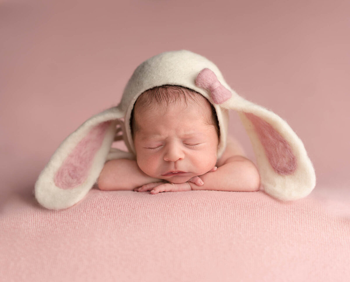 Newborn wearing rabbit ears sleeping