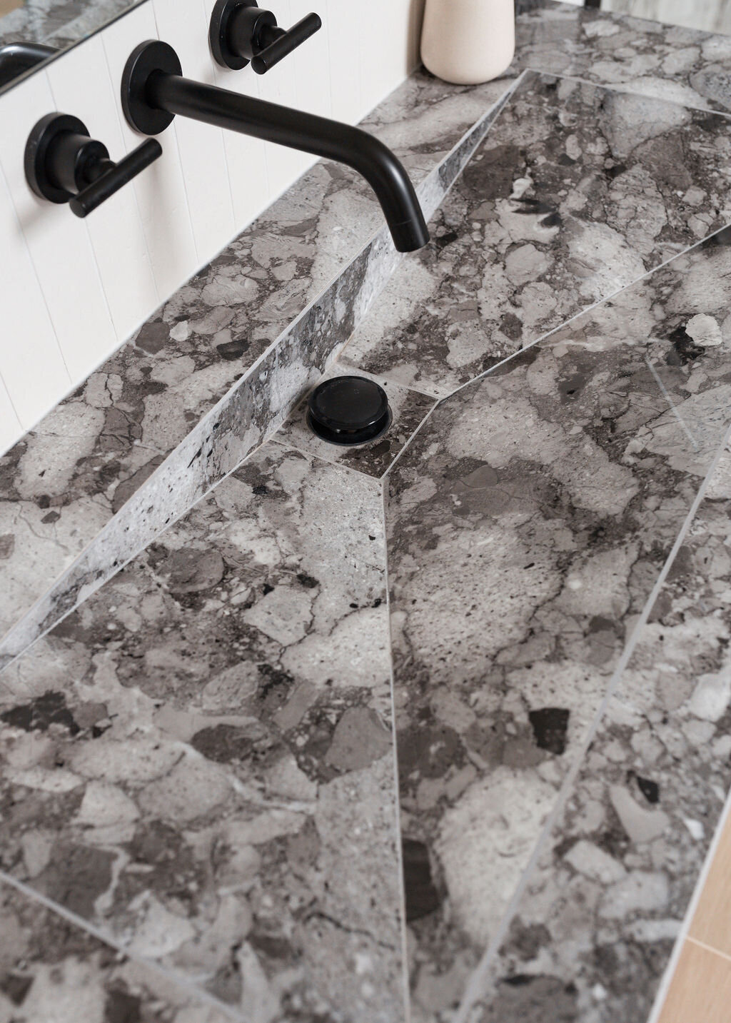 Close-up view of a grey marble bathroom vanity with a built-in sink and matte black fixtures.