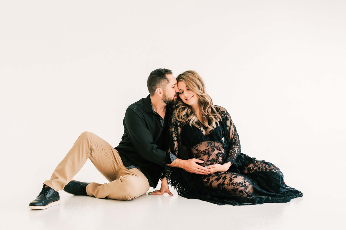 maternity photo of pregnant couple cuddling on floor in maternity photography studio in Springfield MO