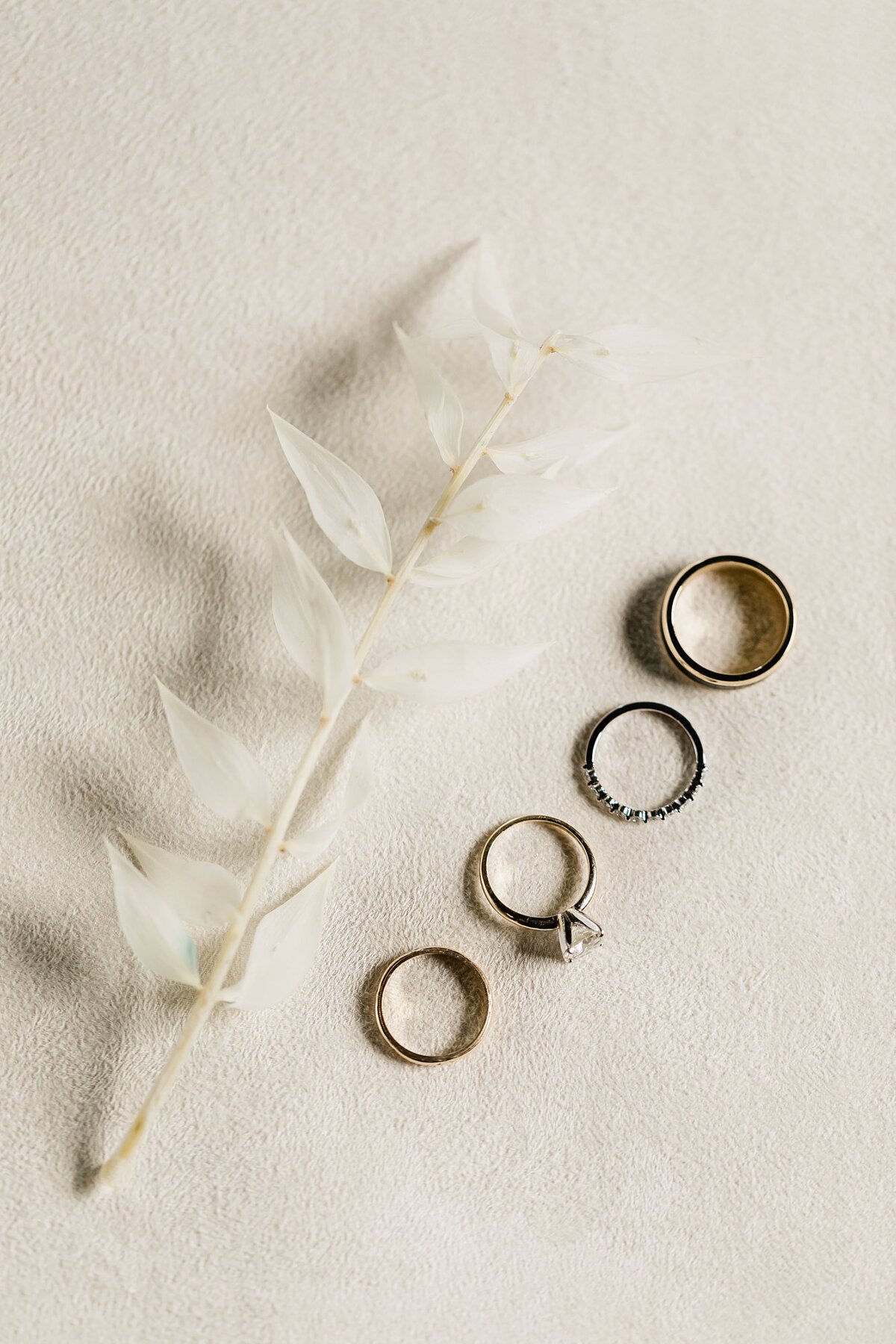 Flatlay of wedding rings with a flower for Morgan and Jimmy's Olde Dobbin Station wedding