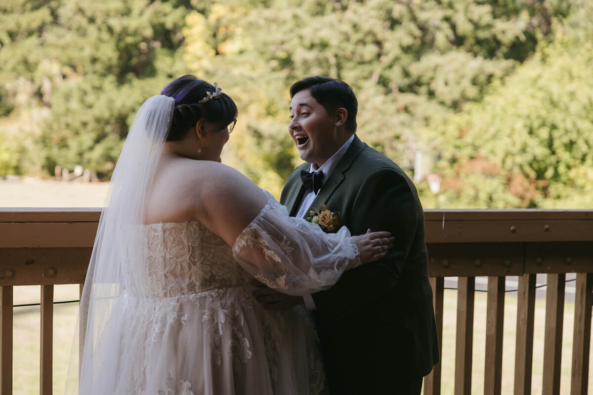 A couple happily embraces during their first looks at their outdoor wedding planned by Birdie June Events.