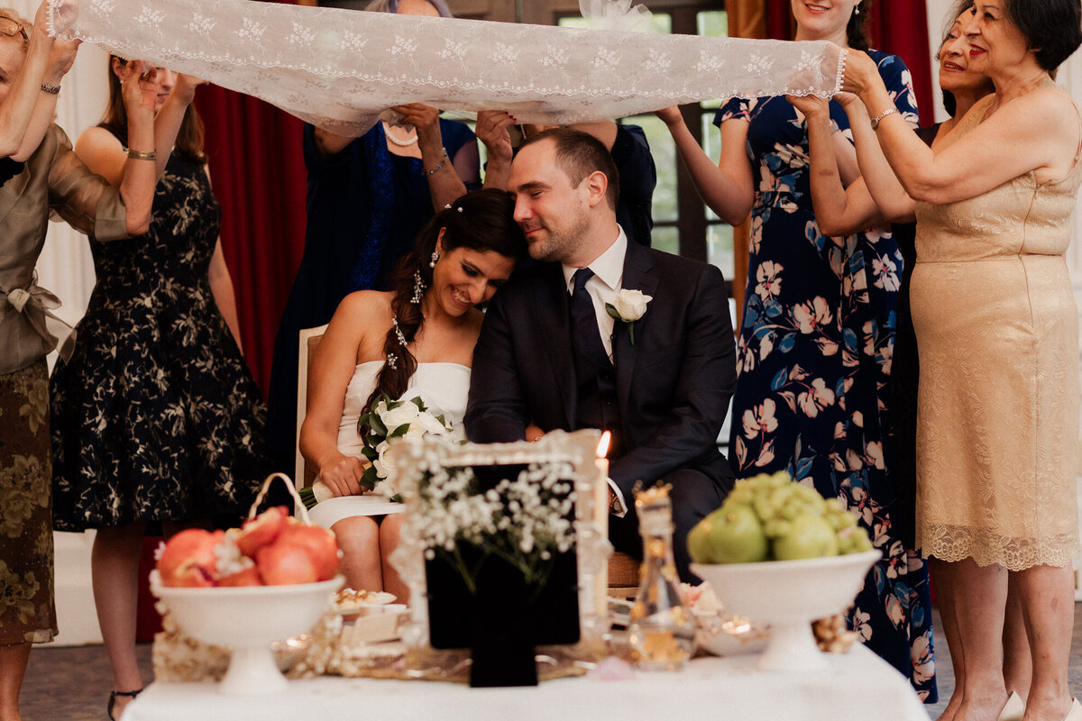 Wedding guests holding fabric over a newlywed couple 