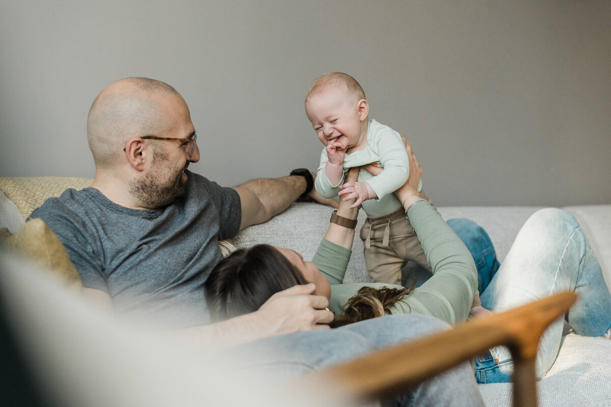 Cute moment of couple holding baby on their couch.