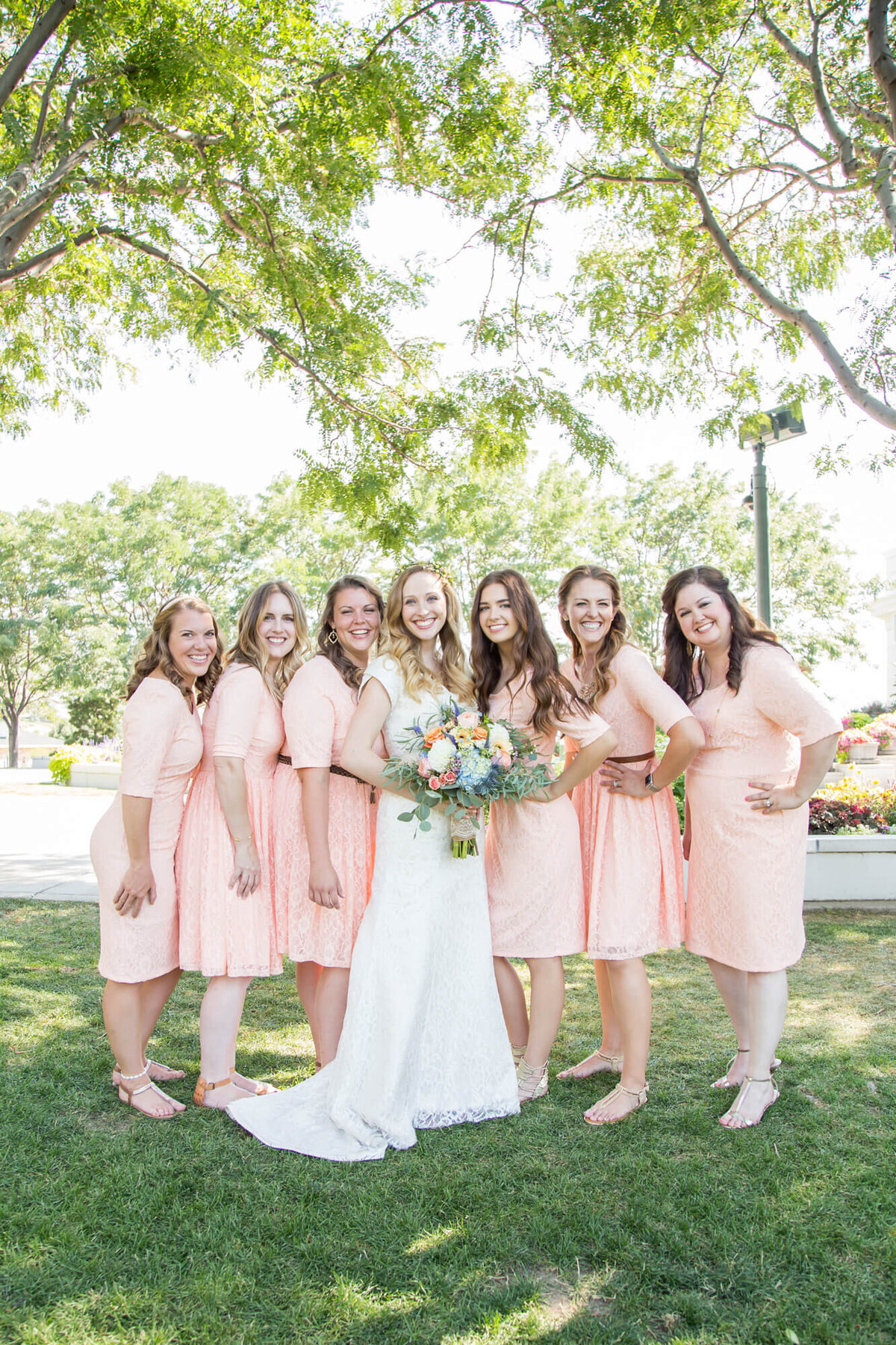 light and airy bridal party portrait of bride in classic lace dress and bridesmaids in light pink. captured by las vegas wedding pro