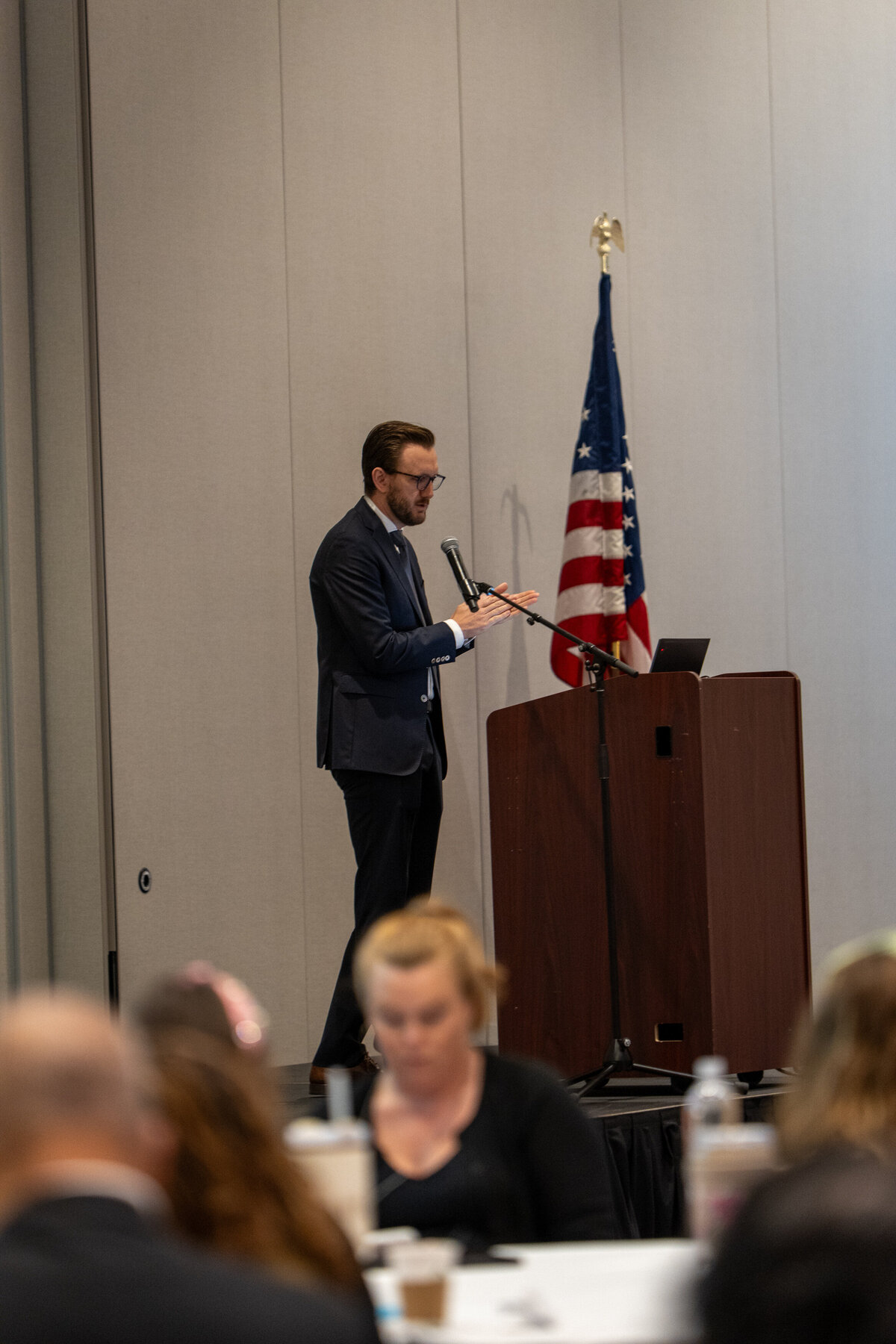 A person in a suit speaking at a podium 