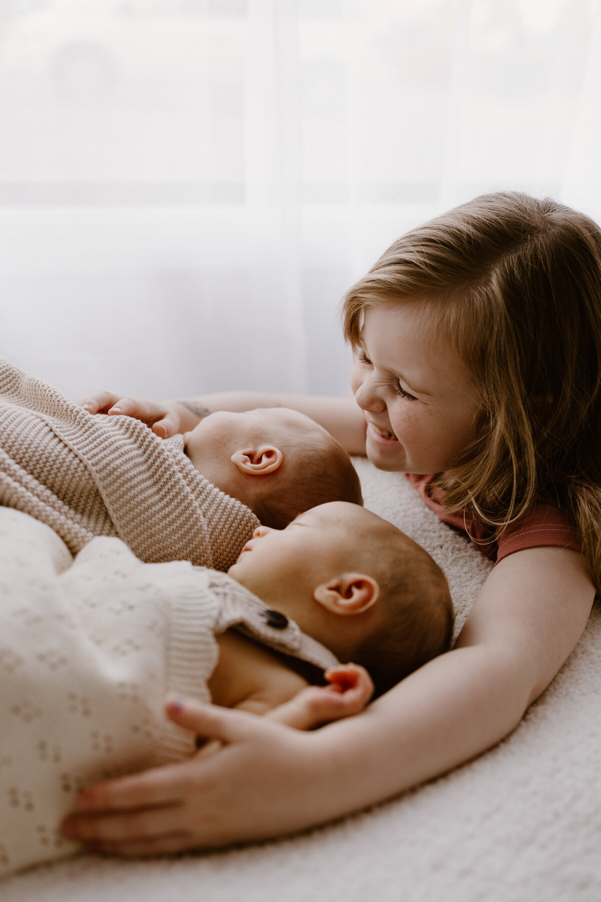 Big sister smiles down at her new twin siblings.