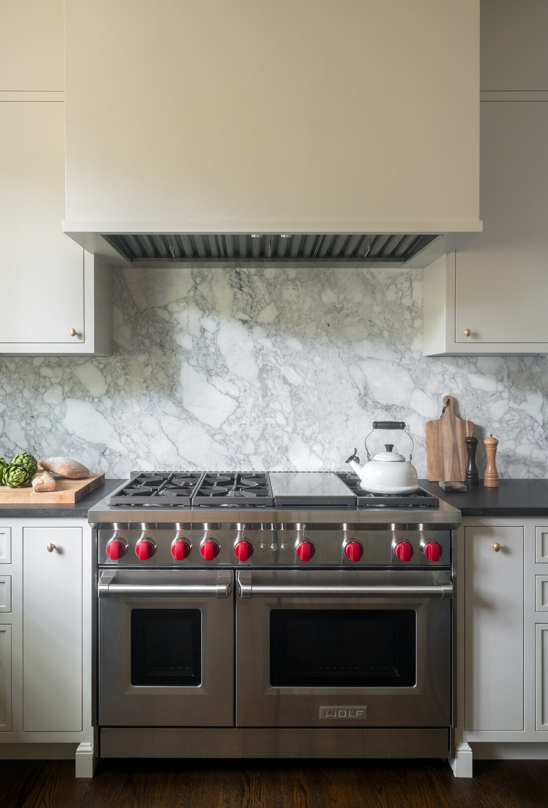 stainless gas stove with built-in range hood and gray marble backsplash