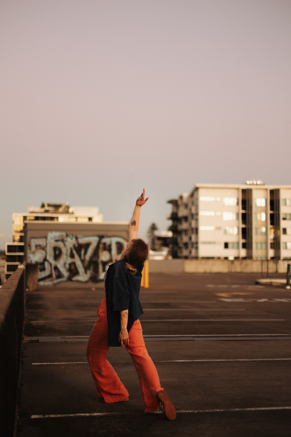 	Empowering brand image taken by a Sunshine Coast branding photographer — woman pointing skyward on a gritty rooftop.