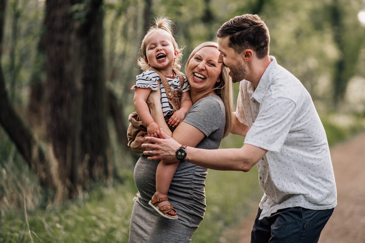 A young family soon expecting their second child plays and laughs during a photo session by Kate Simpson, Minneapolis maternity photographer.
