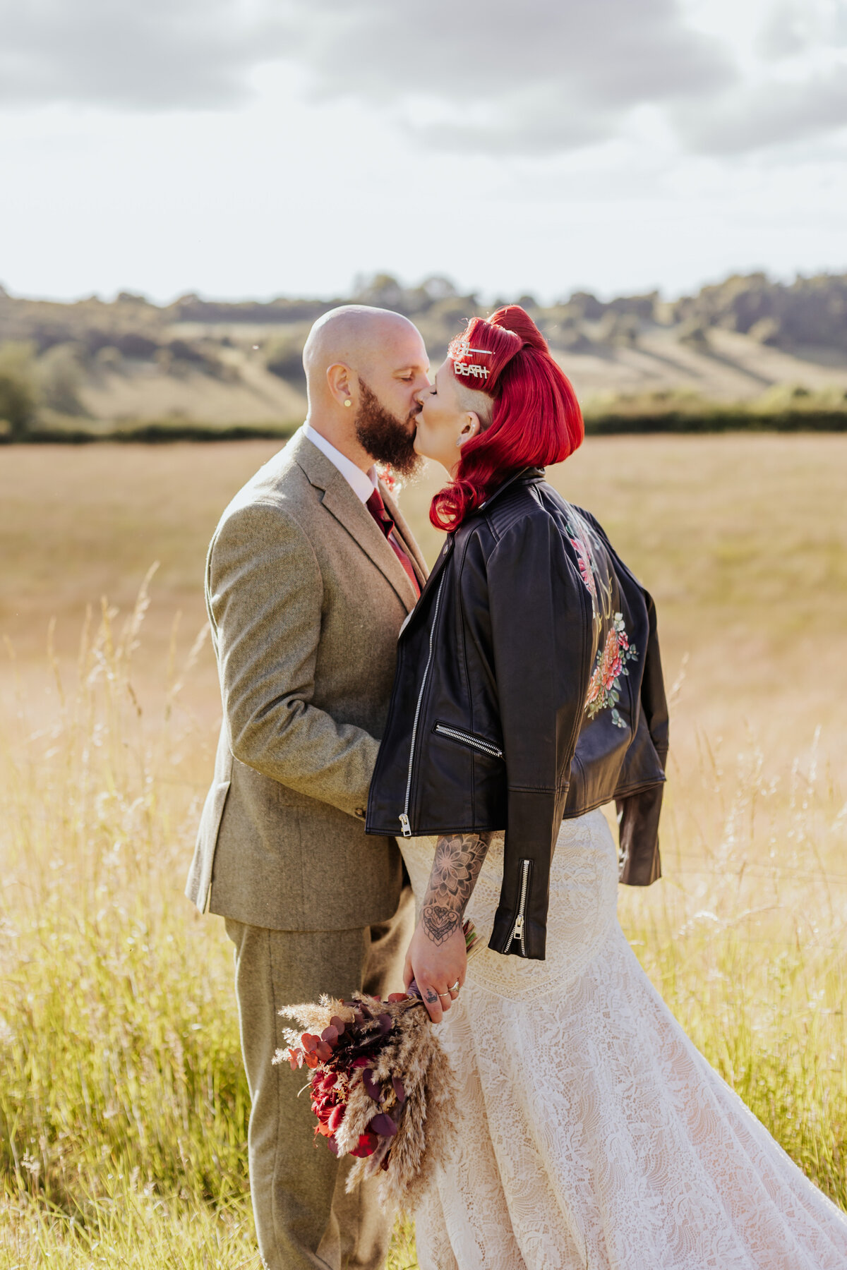 Groom and pin-up style bride kiss during golden hour infront of rolling fields