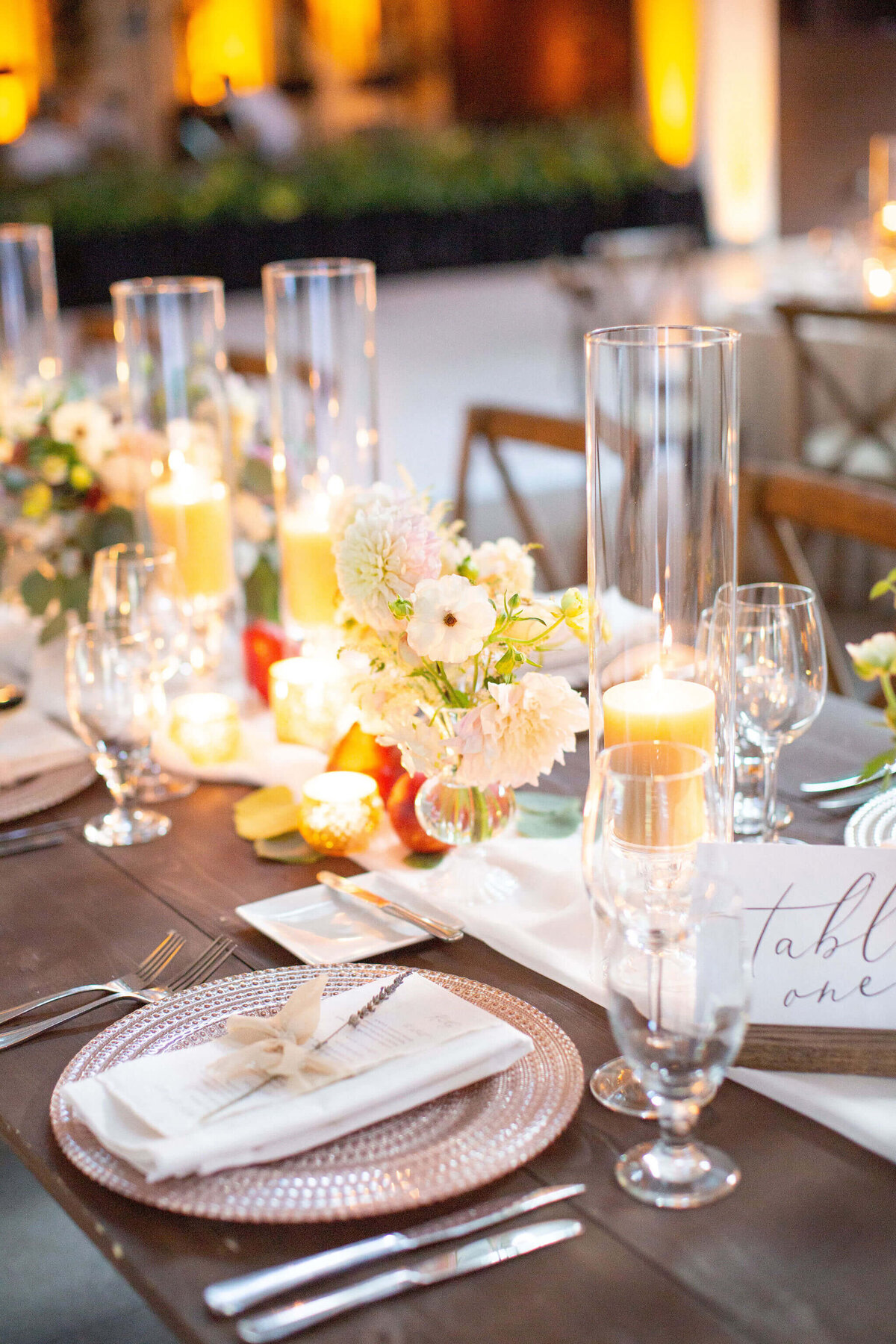 dinner table set for a wedding reception with glowing lights on a stage in the background