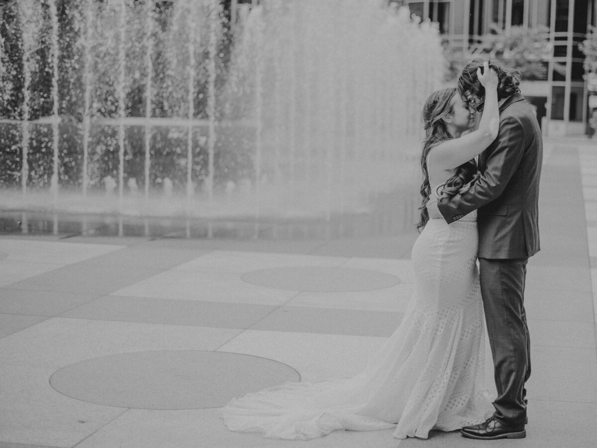 Bride and Groom kissing in front of a fountain