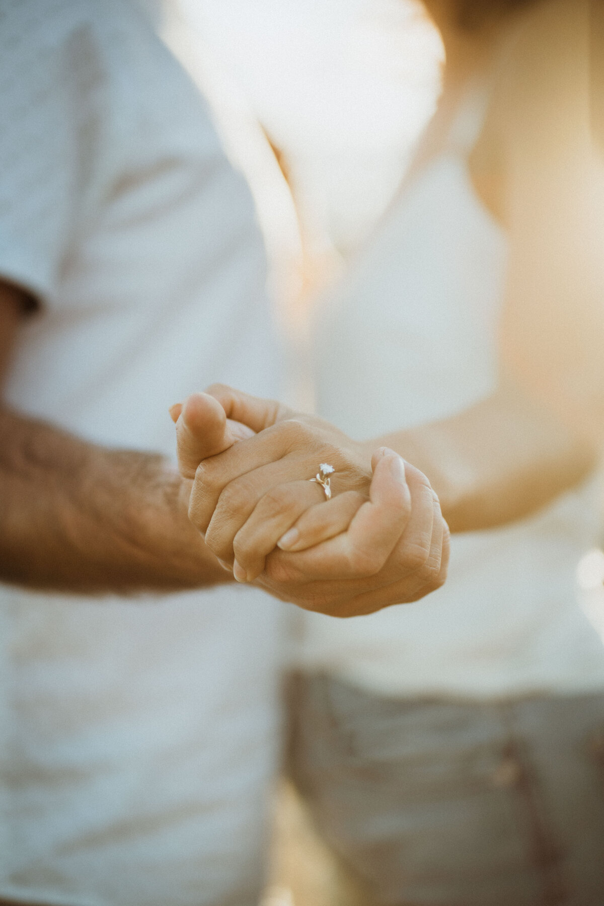 Close up photo of couple holding hands and engagement ring