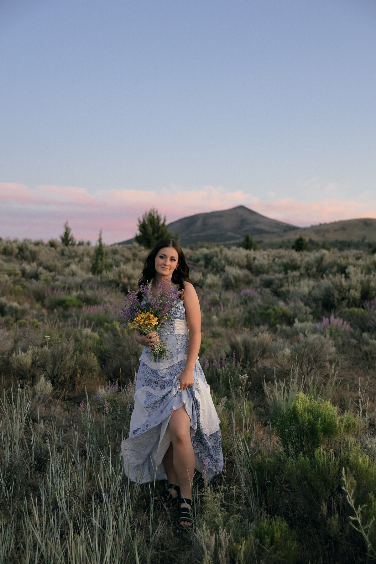 Dreamy Senior Portrait of Girl Sitting Among White Daisies in Blooming Wildflower Field