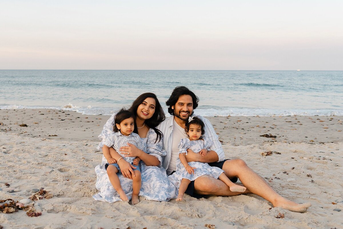 family sitting on beach by family photographer boston ma​