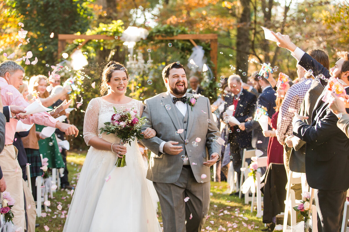 bride and groom walking through tossed flower petals during ceremony recessional