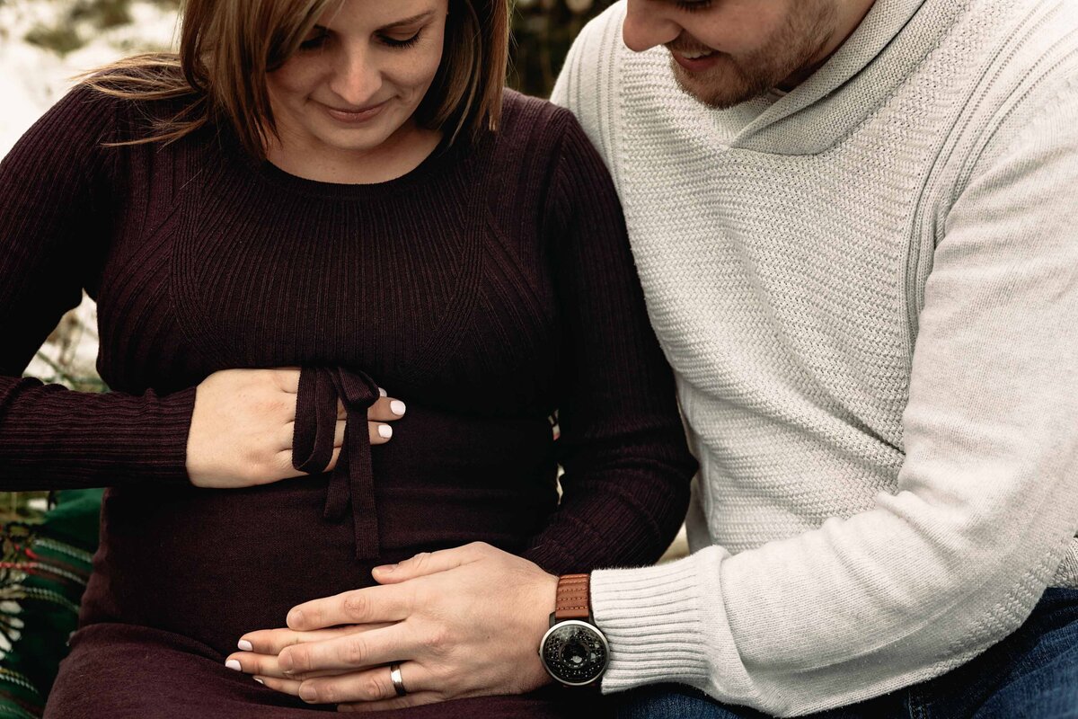maternity photos in london ontario mom and dad looking at belly