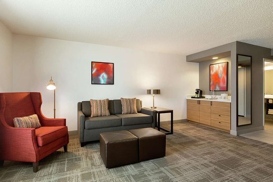 Modern hotel guest room with red lounge chair and grey couch