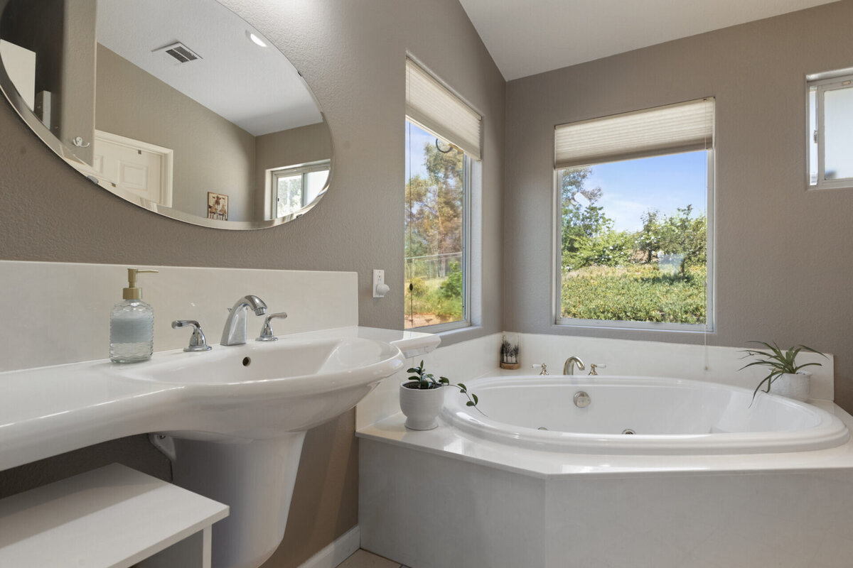 Primary bathroom with a single sink and soaking tub with a view to the backyard. Real Estate home in Ramona