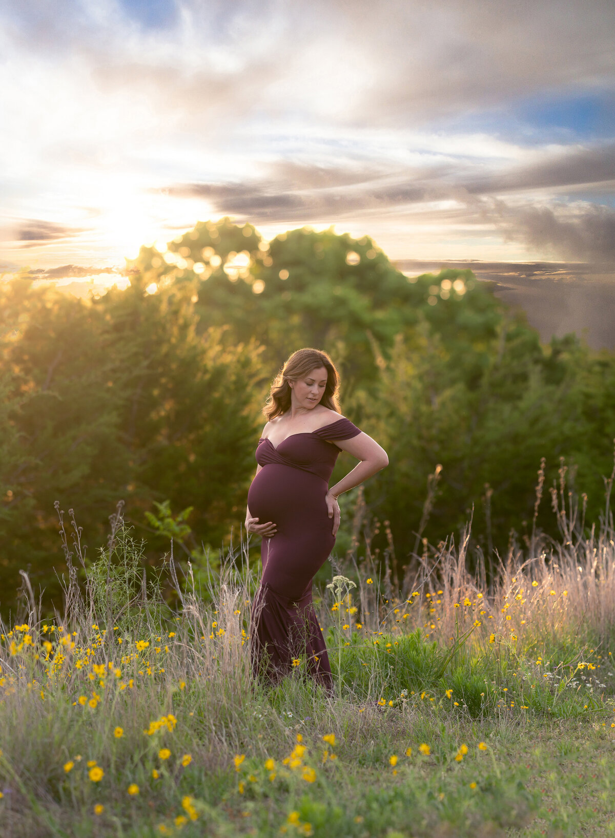 Pregnant woman purple fitted maternity dress and a field of flowers