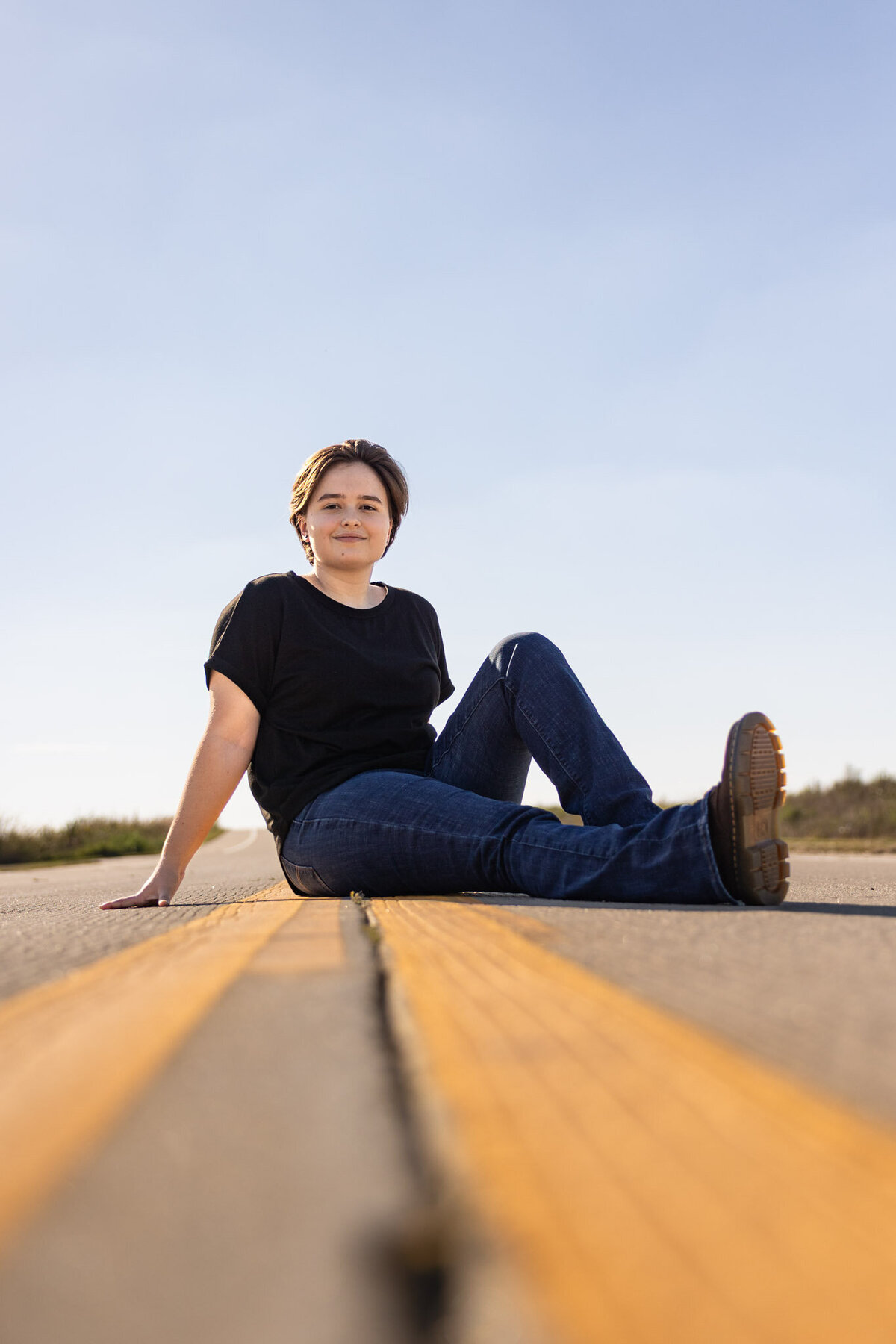 Senior girl sitting casually in the road during a senior session in Lawrence KS