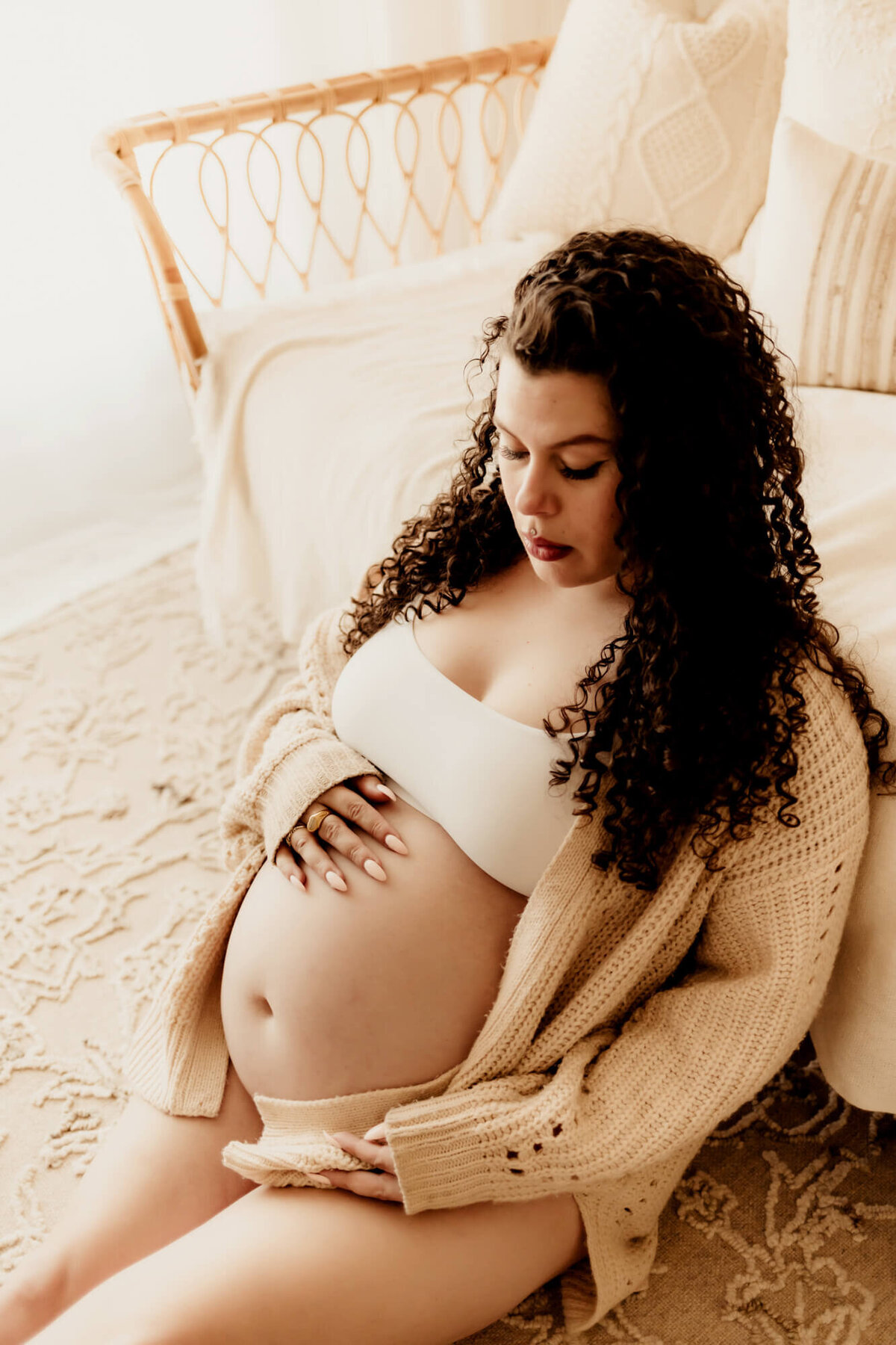 Expecting mother with curly hair looks at her belly. 