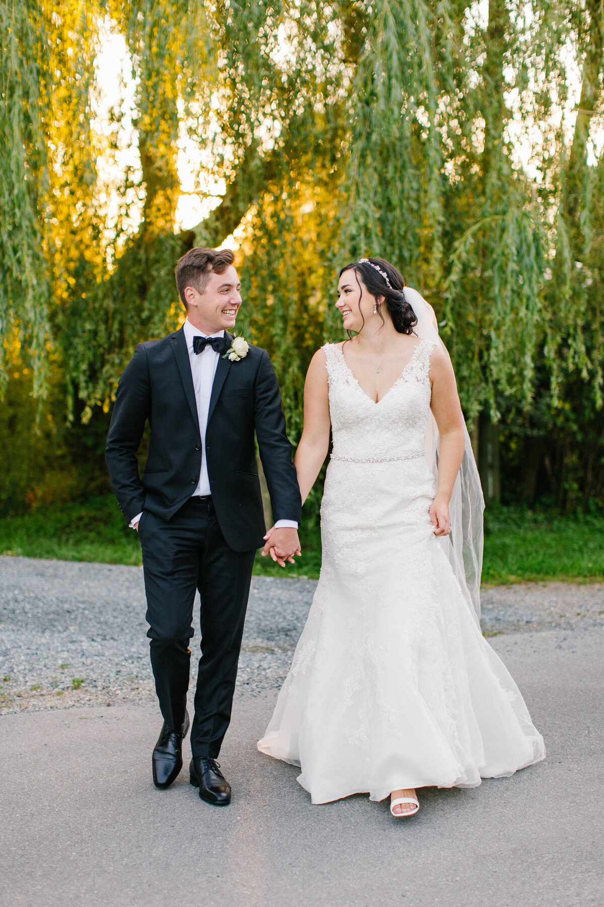 Bride and groom holding hands and walking while smiling at each other