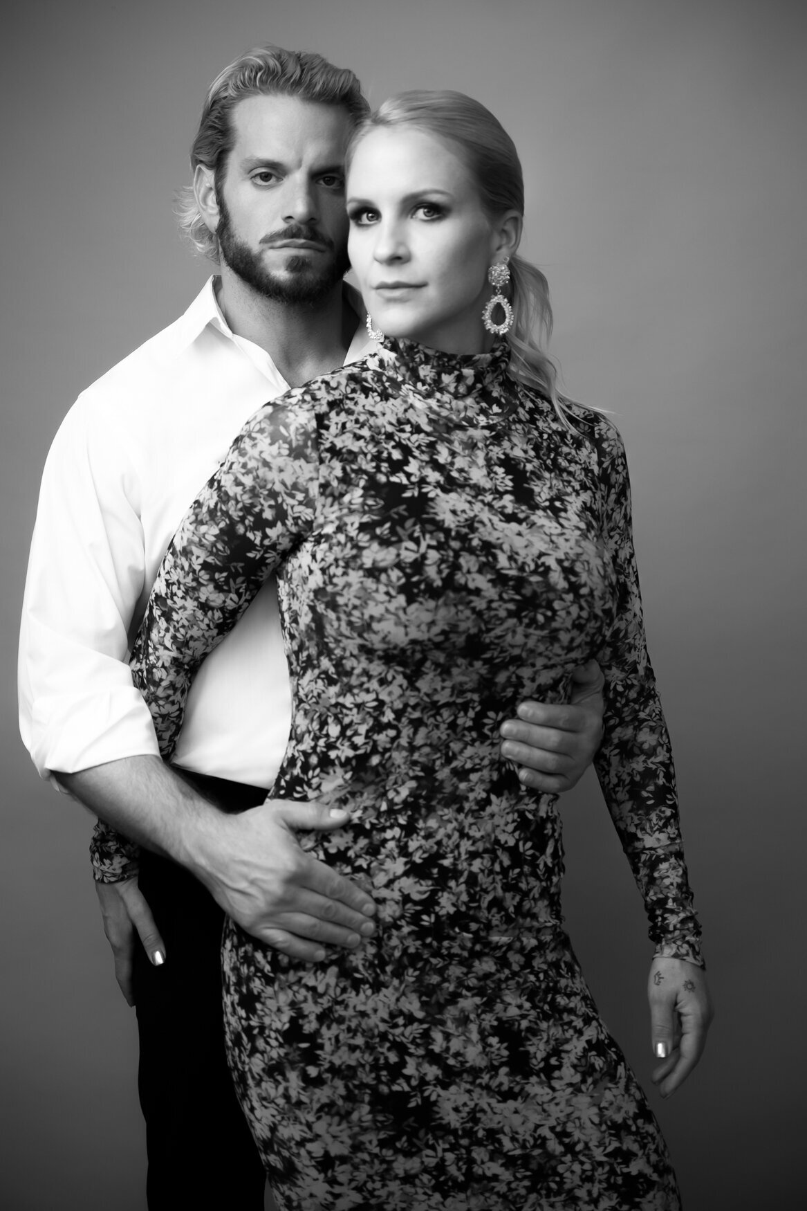 portrait of a couple hugging. the man is behind her grabbing her from the waist