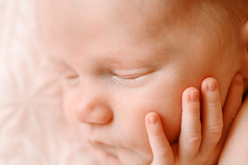 Close up image of a newborn baby with it's hand on it's face by Los Angeles Newbonr Photographer Daniele Rose