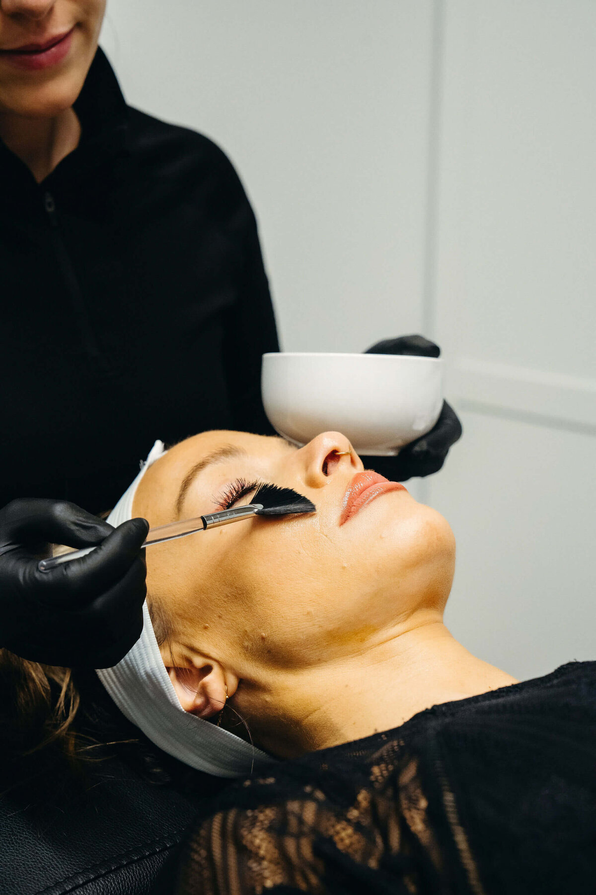 Client receiving a chemical peel during facial treatment at Maxwell Aesthetics in Salem, Oregon, with provider applying solution using a fan brush