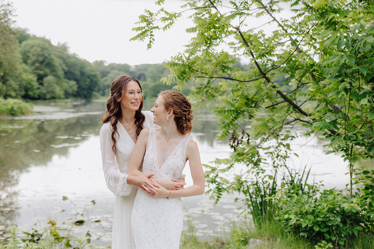 Brides standing by at lake at Cornell University wedding