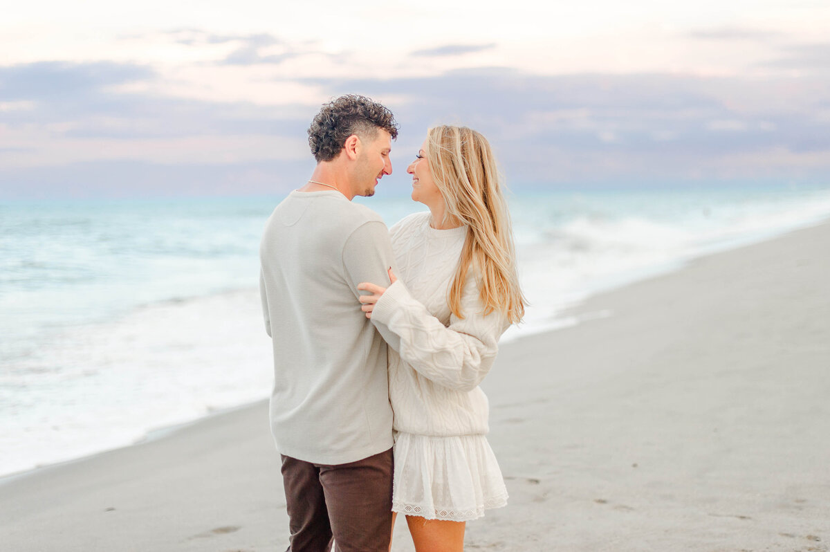 Orlando engagement photographer captures newly engaged couple near the ocean water at sunset