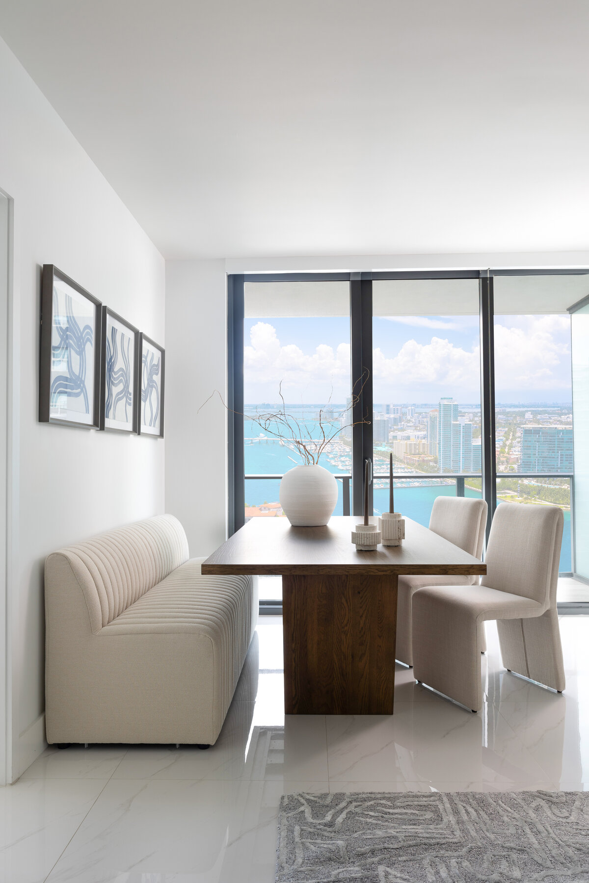 minimal, neutral, bright and airy dining room. wood oak table, cream boucle chairs. miami condo