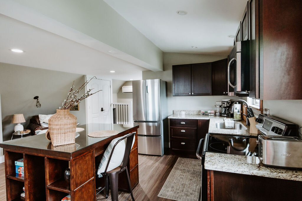 a fully stocked kitchen with appliances and an island in the willowbrook wedding venue overnight cottage suite