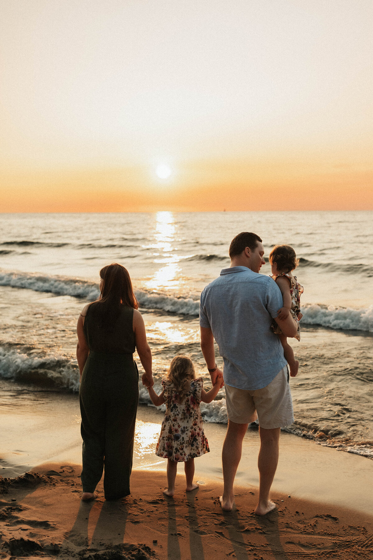 family watches sunset together during photoshoot in st joseph michigan