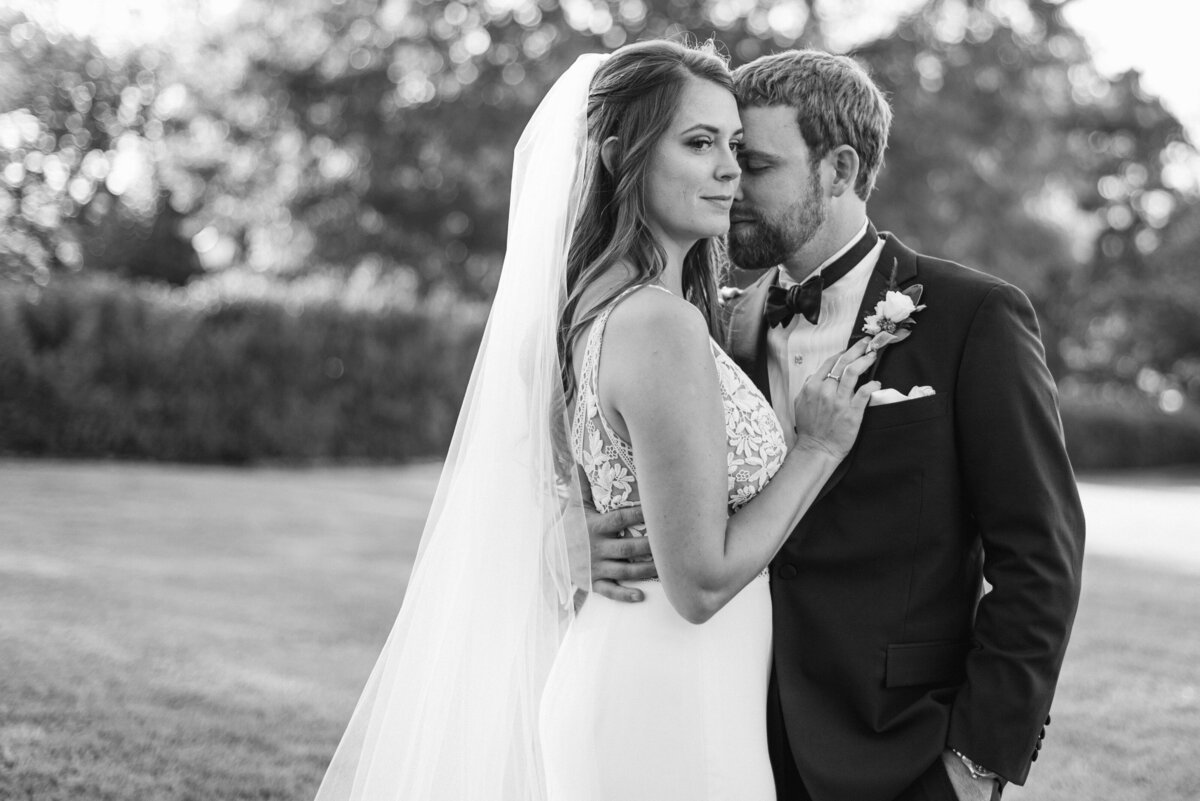 black and white image of a couple embracing while the bride looks off