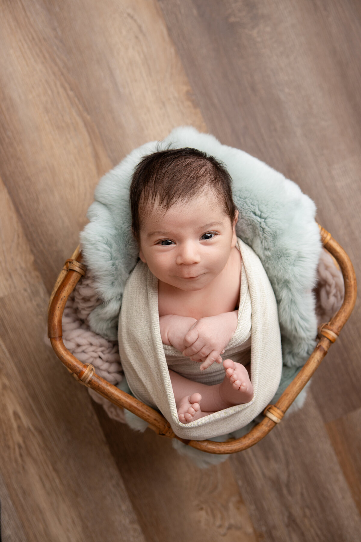 Wrapped newborn baby boy with mint luneberry stuffer and bamboo basket