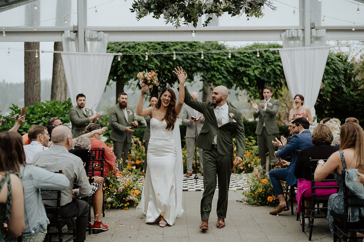 Bride & groom recessing down the aisle with big smiles and their hands in the air!