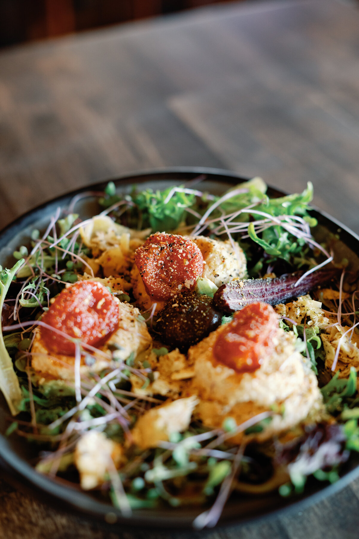 Stuffed Avocados. A vegan friendly meal that includes fresh mixed greens, hummus, avocados, tomatoes, purple carrots and mirco greens form a local supplier