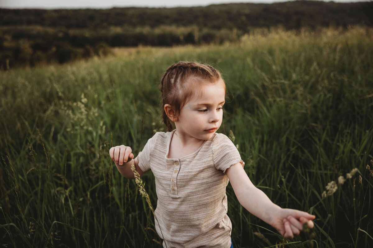 little girl in tall grass in portrait session with reva davis photography