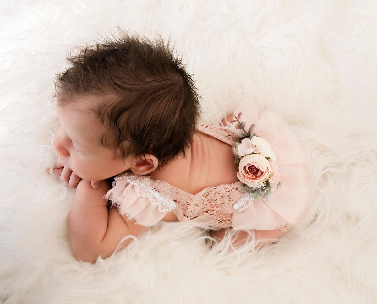 Newborn baby girl photo in an Erie Pa photography studio wearing a pink romper