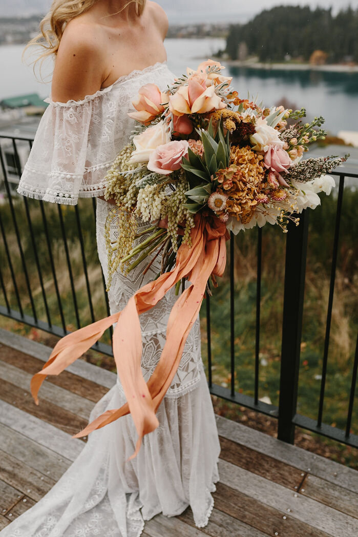 The Vase Floral Co - bride holds large flowing bouquet in peach and light tone flowers