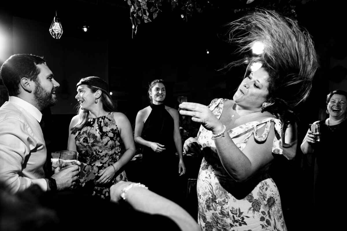 Black and white photograph of wedding guest hair flying while dancing at Eventide Brewing by Charlotte wedding photographers DeLong Photography