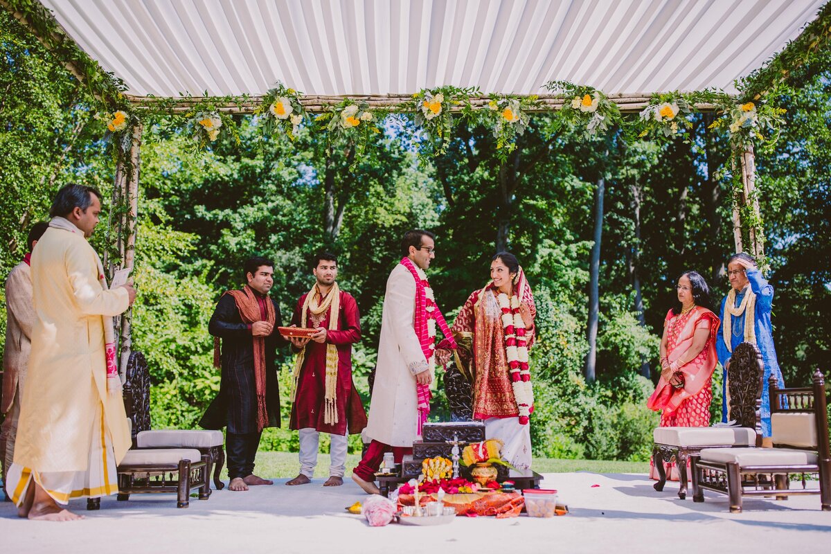 indian bride and groom smile at each other as they walk around the fire during their hindu ceremony at the hilton pearl river