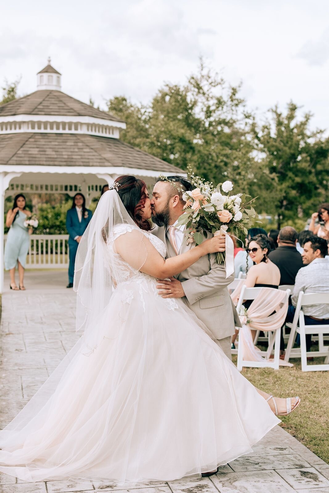 bride and groom kiss and dip at the end of the aisle while exiting the ceremony