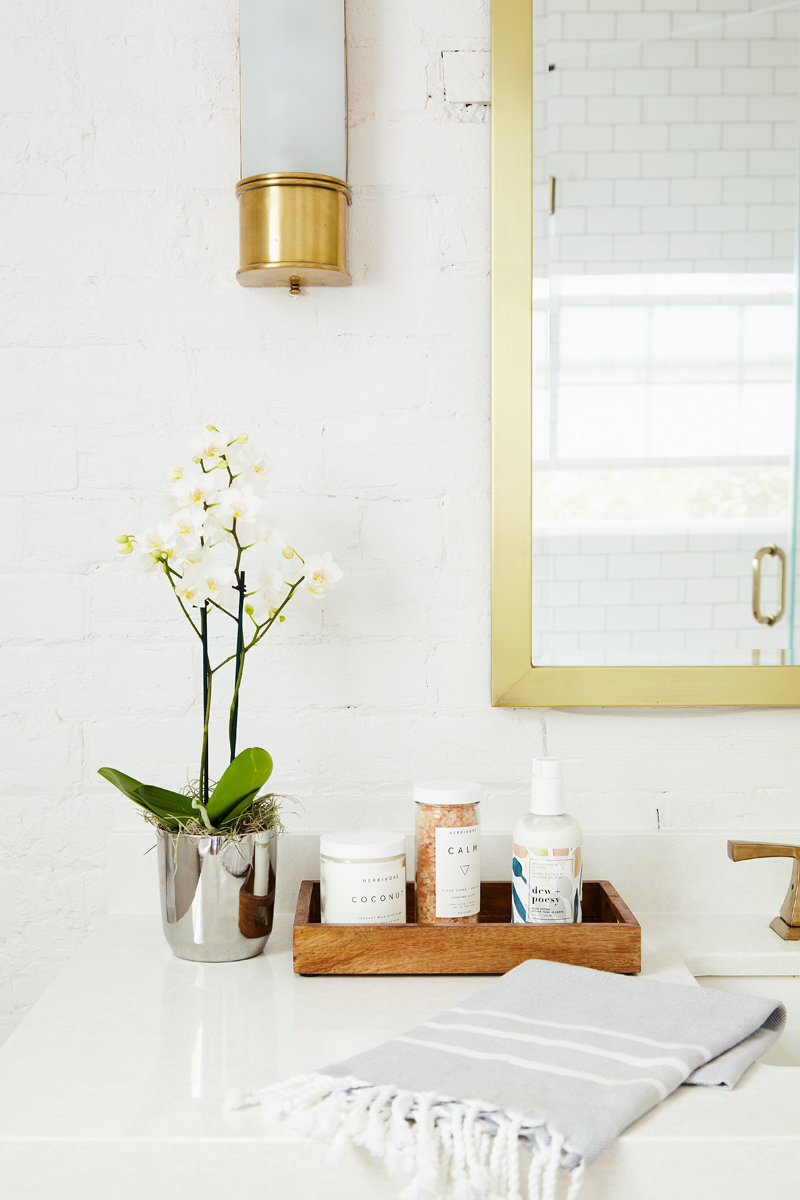 white bathroom with painted brick wall and gold interior fixtures